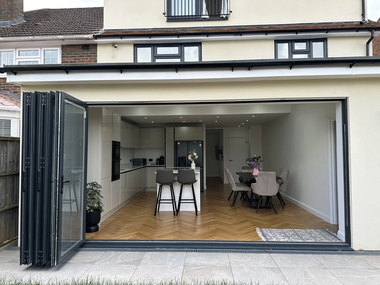 Single-storey rear extension with aluminium bifold doors opening onto the patio by Alb Homes in Borehamwood