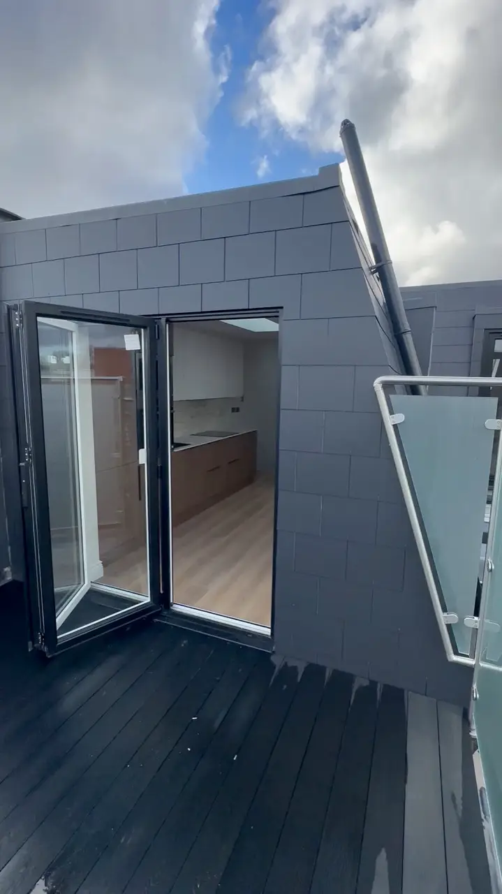 Roof terrace with glass balustrade and bifold doors into the converted loft by Alb Homes in White City